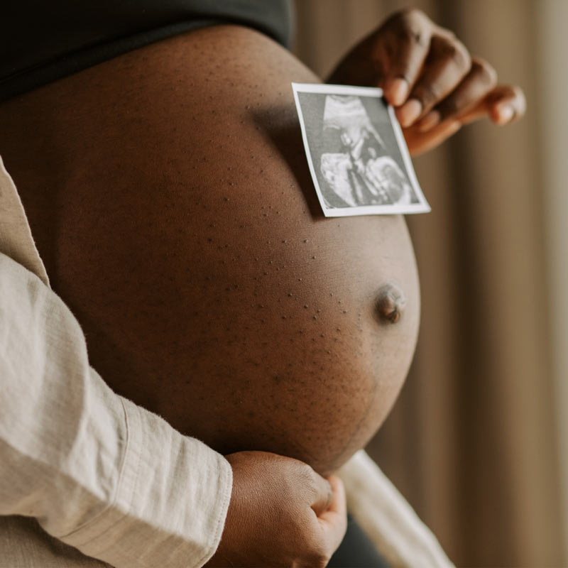 Pregnant person with baby scan picture