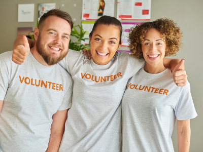 3 volunteers smiling with arms around each other!