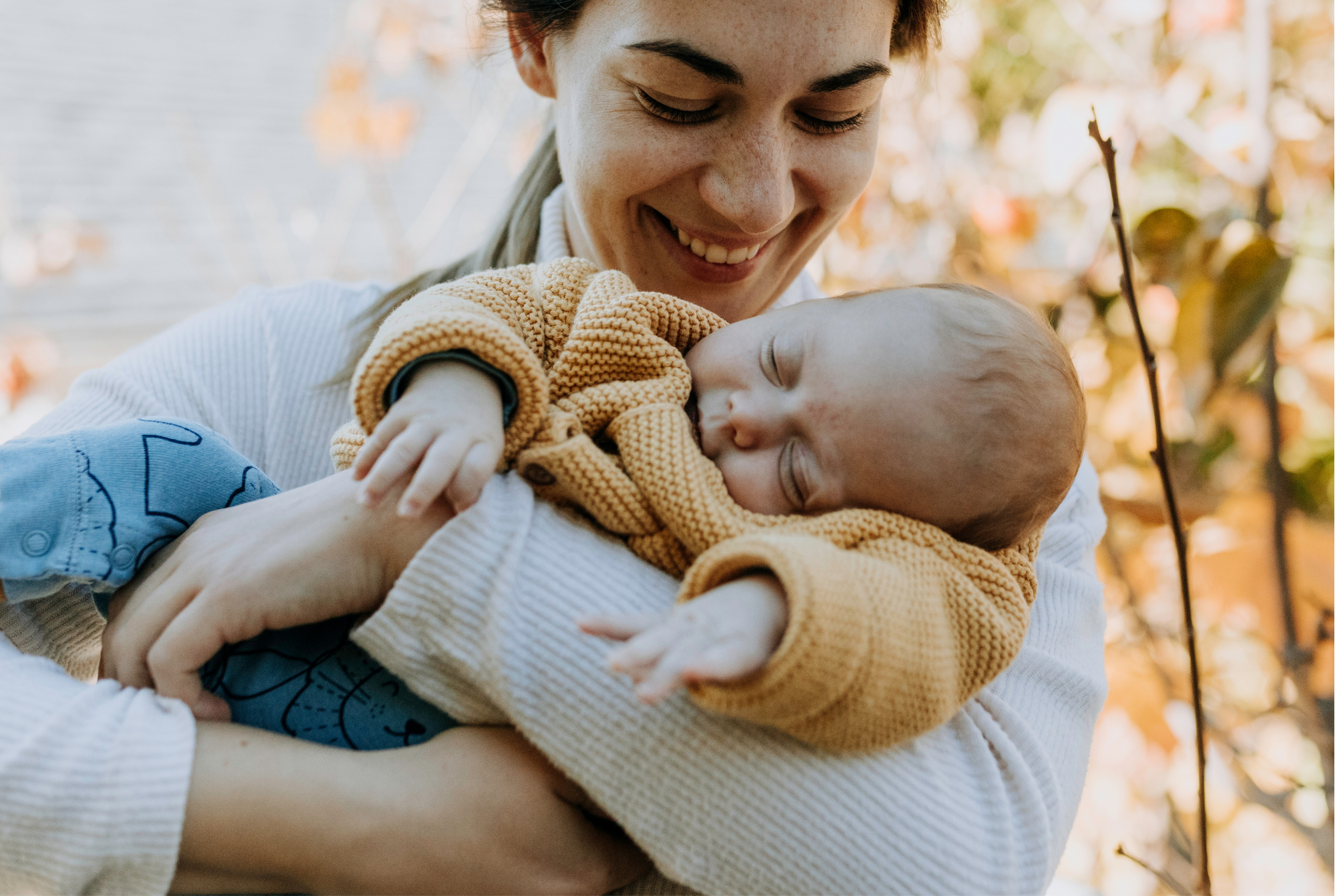mum holding a 2 month old baby in her arms, smiling